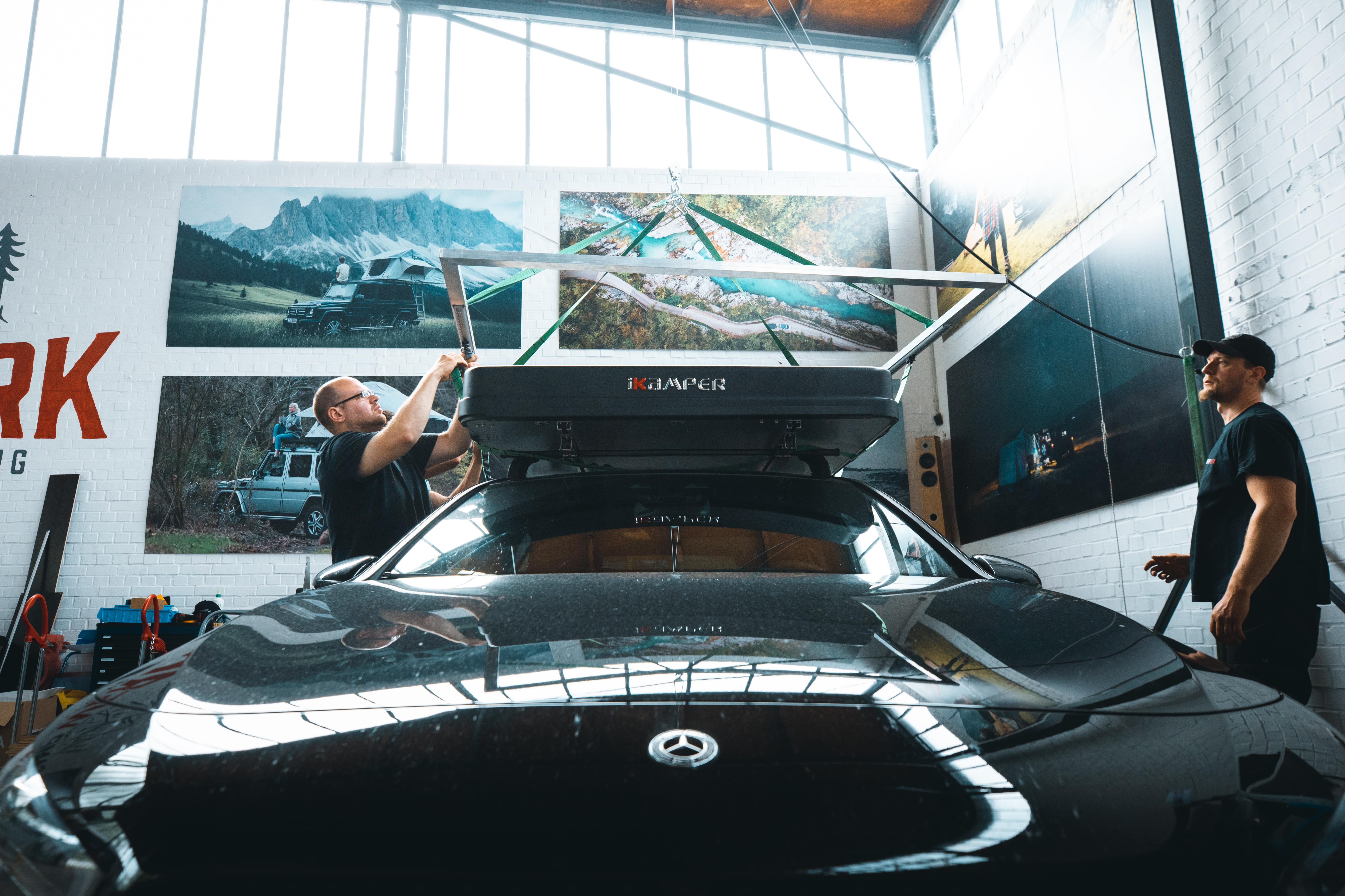 Medewerker van CAMPWERK monteert een daktent op een zwarte auto