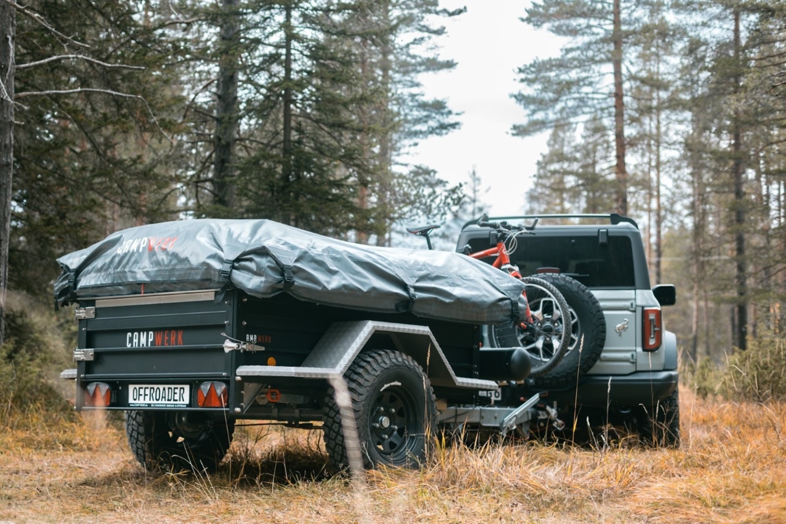 Een wagen met afgekoppelde tenttrailer op een bospad